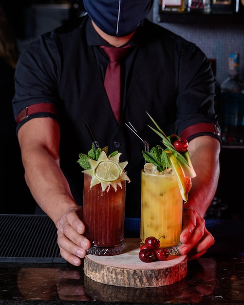 A young professional bartender prepares cocktails for his clients at work profession concept