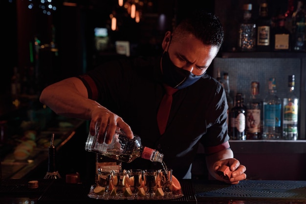 A young professional bartender prepares cocktails for his clients at work profession concept