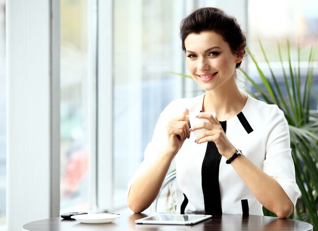 Young professional businesswoman sitting at table at cafe