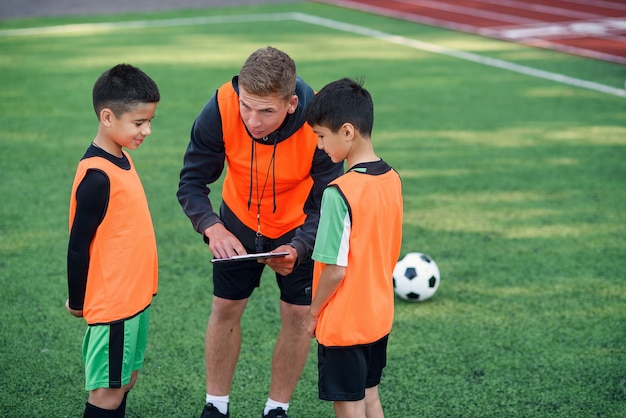 Young professional coach explains for kids the strategy of the game