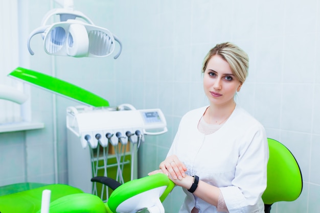 Young professional doctor dentist in a modern office with dental equipment. The concept of health insurance and free dental care. Prosthetics and installation of veneers.