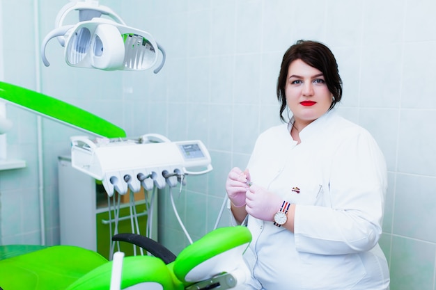 Young professional doctor dentist in a modern office with\
dental equipment. the concept of health insurance and free dental\
care. prosthetics and installation of veneers.