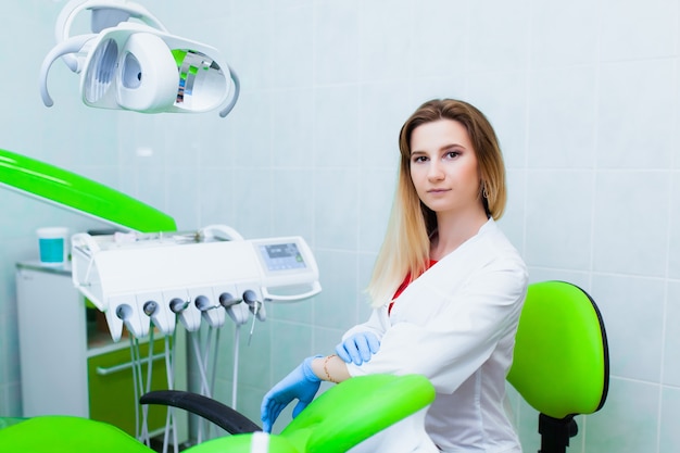 Giovane dentista medico professionista in un ufficio moderno con apparecchiature odontoiatriche. il concetto di assicurazione sanitaria e cure dentistiche gratuite. protesi e installazione di faccette.