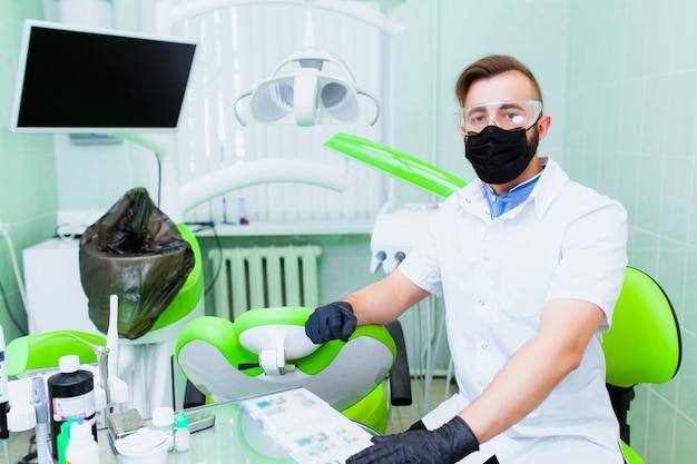 Young professional doctor dentist in a modern office with
dental equipment. the concept of health insurance and free dental
care. prosthetics and installation of veneers.