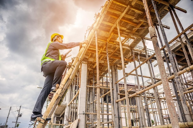 Photo young professional engineer worker working on ladder at the house building construction site