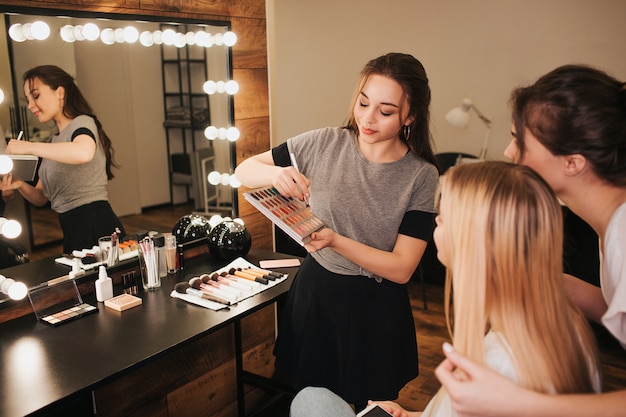 Young professional makeup artists with client in the room