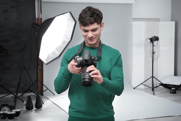 Young professional photographer with camera in studio