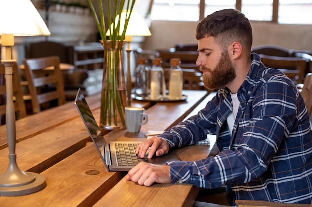 커피숍이나 홈 오피스의 탁자 위에 커피 한 잔을 올려놓고 노트북으로 인터넷 서핑을 하는 젊은 전문가, 카페 컨셉에서 일하는