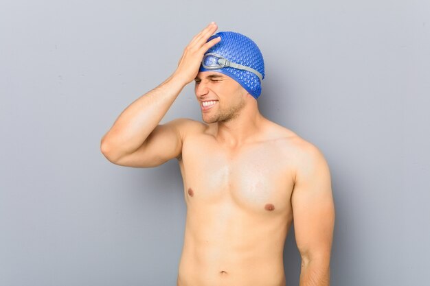 Young professional swimmer man forgetting something, slapping forehead with palm and closing eyes.