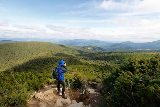 屋外の幻想的な山の風景を撮影するデジタル一眼レフカメラを持つ若いプロの旅行者の男