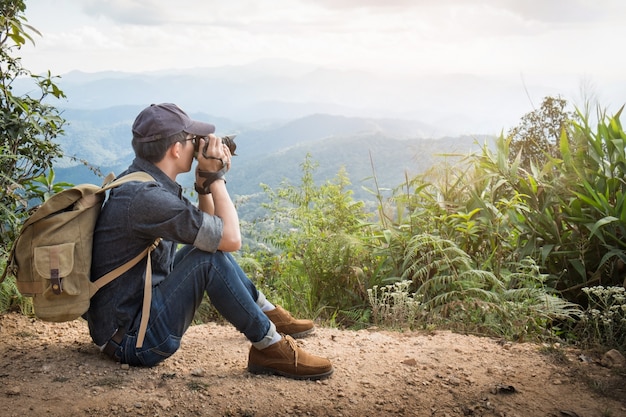 Young professional travrler man with camera shooting outdoor, fantastic mountain landscape