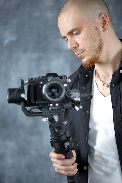 Photo a young professional videographer shoots video using camera on a 3-axis gimbal stabilizer