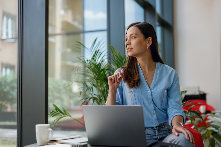 Photo young professional woman is focused on her laptop work at a bright modern office desk by the window