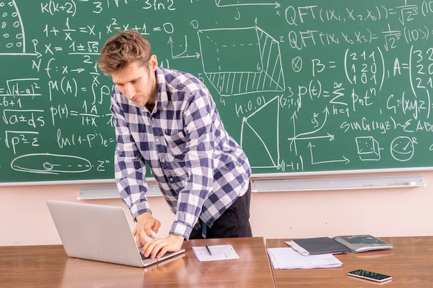 Young professor proving theorem on a blackboard b