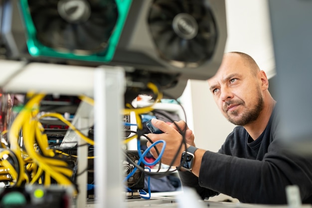 Young programmer adjusting cryptocurrency mining rig to optimal operational settings. High quality photo