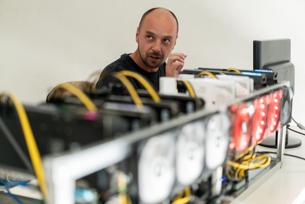 Young programmer adjusting cryptocurrency mining rig to optimal operational settings. High quality photo