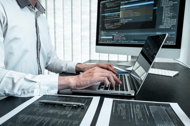 Фотография молодой программист, работающий над программным javascript-компьютером в ит-офисе, пишет коды и веб-сайты с кодами данных и кодирует технологии баз данных для поиска решения проблемы.