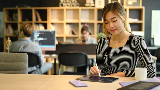 Giovani programmatori o sviluppatori di software che utilizzano tablet digitale che lavorano in un ufficio moderno