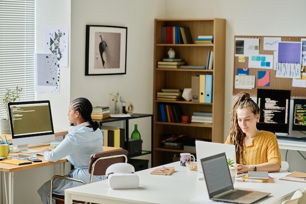 Young programmers working on computers at their workplaces in it office