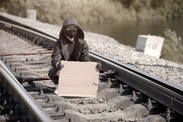 Foto una giovane donna protestante si siede sulla ferrovia e guarda la telecamera