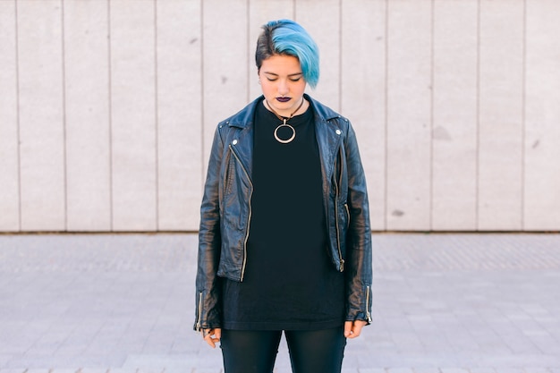 Young punk woman with blue dyed hair and a leather jacket looking down