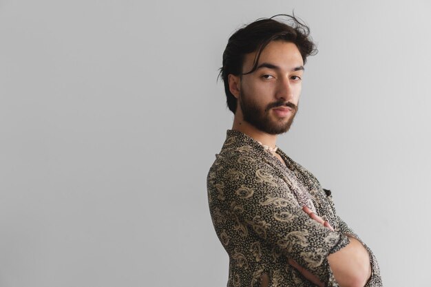 Young queer latin gay man in profile with his arms crossed looking at the camera Copy space