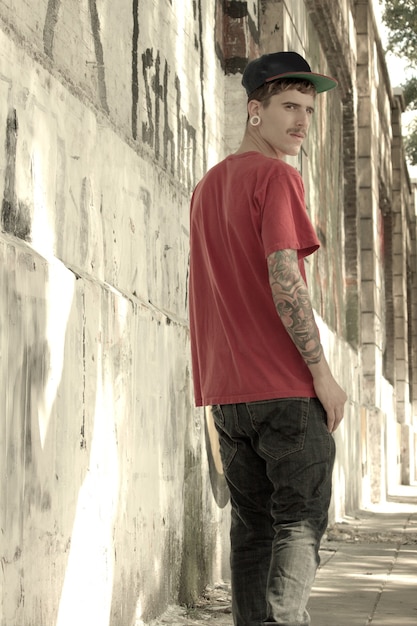 Photo a young rapper leaning against a wall.