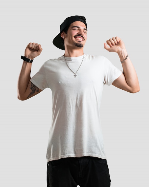 Foto giovane uomo di rapper ascoltando musica, ballando e divertendosi, muovendosi, gridando ed esprimendo felicità, concetto di libertà
