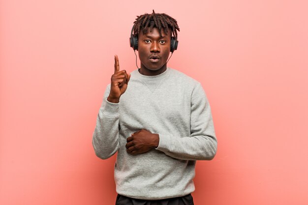 Фото Молодой чернокожий человек rasta слушая к музыке при наушники имея некоторую отличную идею, концепцию творческих способностей.