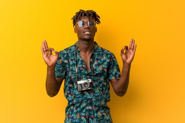 Young rasta man wearing a vacation look relaxes after hard working day, he is performing yoga