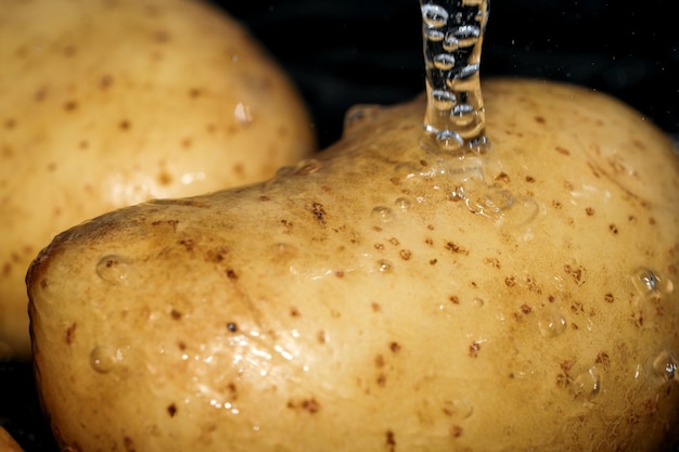 Молодой сырой картофель в кожуре моют в чистой воде перед приготовлением макросъемка крупным планом