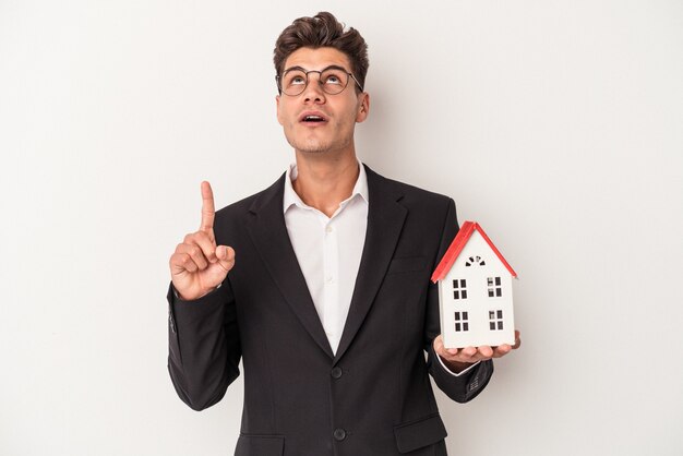 Young real estate caucasian agent isolated on white background pointing upside with opened mouth.