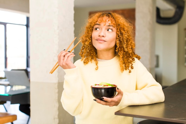 家でラーメン丼を食べる若い赤毛のラテン系のきれいな女性