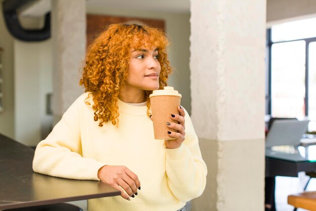 Photo young red hair latin pretty woman with a hot coffee at home