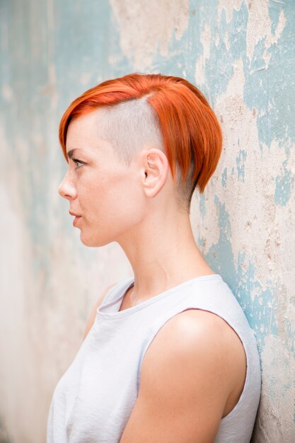 Young red hair woman by the old wall