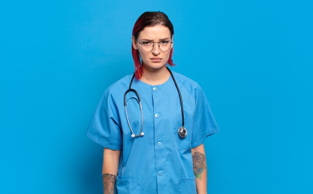 Young red hair woman feeling sad, upset or angry and looking to the side with a negative attitude, frowning in disagreement. hospital nurse concept