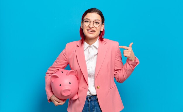 Young red hair woman smiling confidently pointing to own broad smile, positive, relaxed, satisfied attitude. humorous business concept.