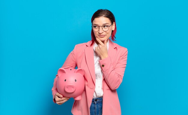 Young red hair woman smiling with a happy, confident expression with hand on chin, wondering and looking to the side. humorous business concept.