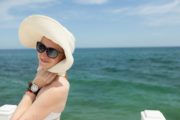 young red-haired girl in a hat on the background of the sea