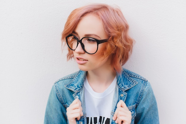 Young red-haired girl with glasses and a denim jacket