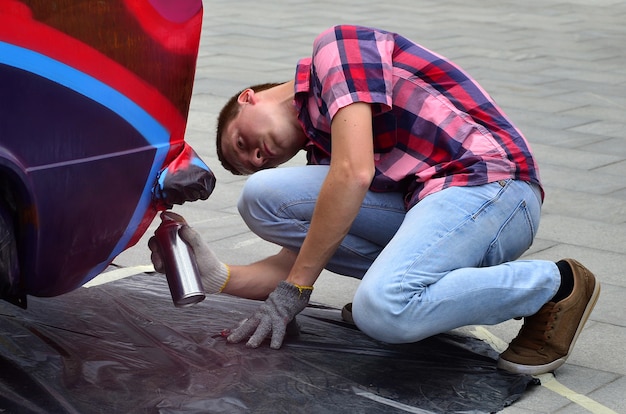 A young red-haired graffiti artist paints a new colorful graffiti 