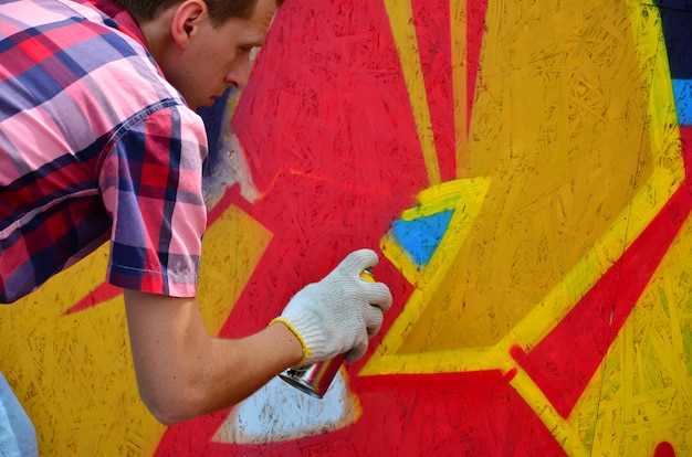 A young red-haired graffiti artist paints a new graffiti on the wall. 