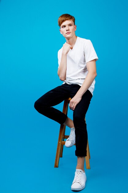 Photo young red-haired man dressed in a white t-shirt and trousers