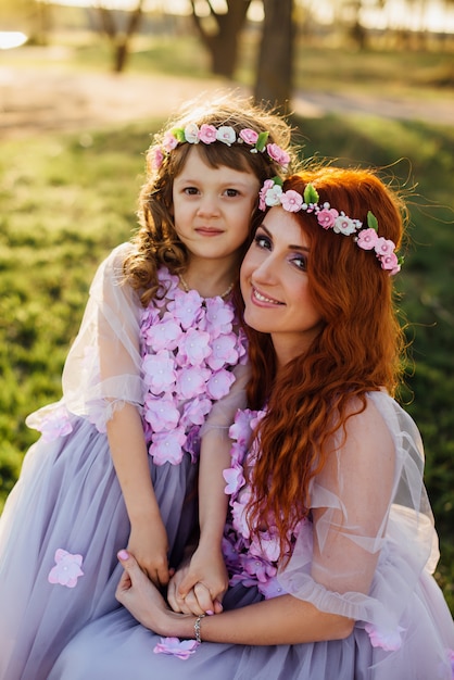 Young red-haired mother with her daughter resting on nature in the sun