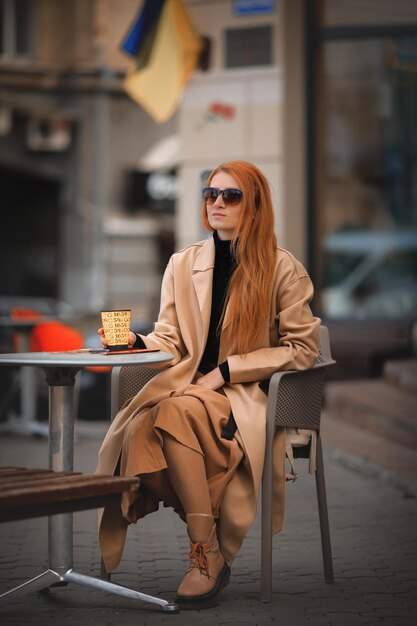 young red-haired woman drinking coffee in a cafe