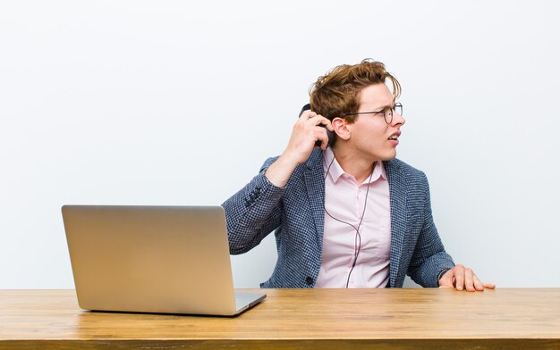 Young red head businessman working in his desk with headphones