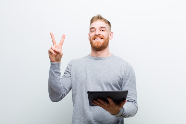 Young red head man holding a tablet against white background