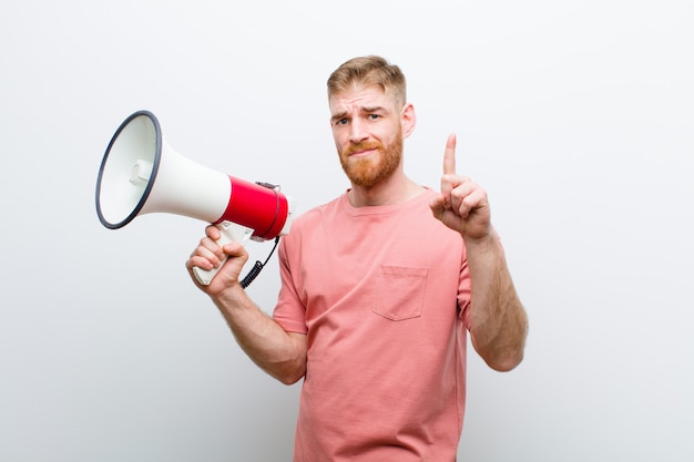 Young red head man with a megaphone against white background