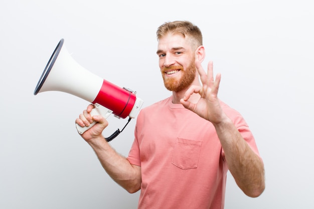 Young red head man with a megaphone against white background