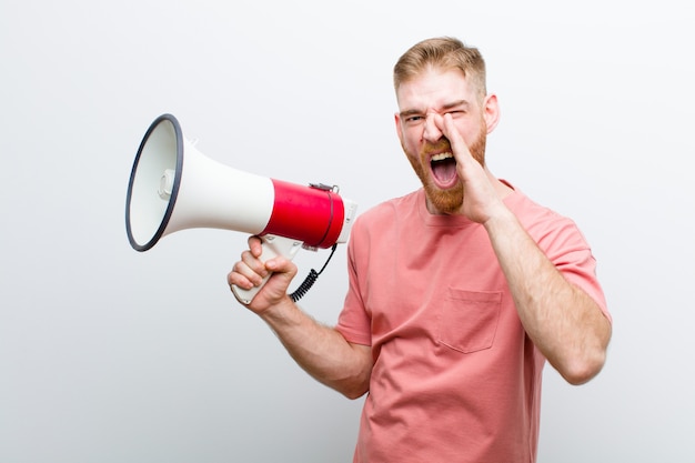 Young red head man with a megaphone against white 